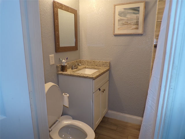 bathroom featuring wood-type flooring, vanity, and toilet