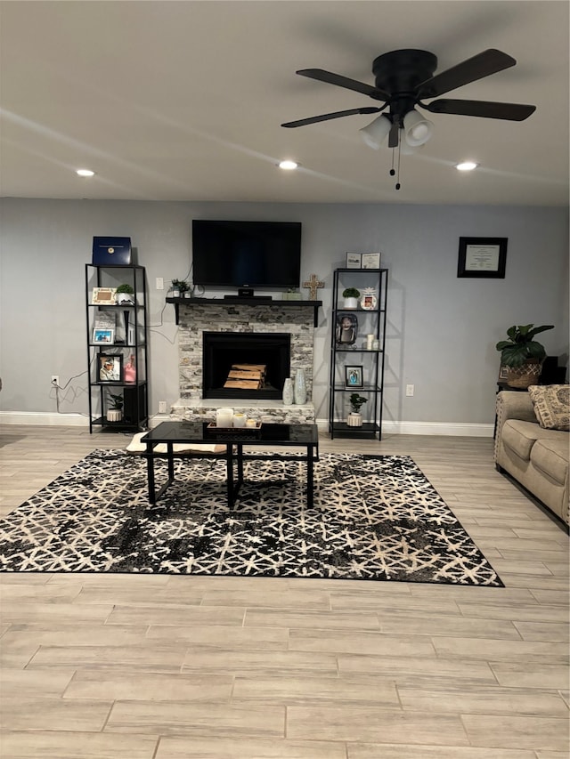 living room with a fireplace, light wood-type flooring, and ceiling fan