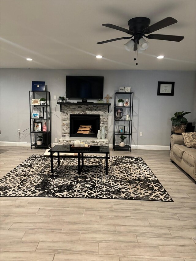 living room with a fireplace, light wood-type flooring, and ceiling fan