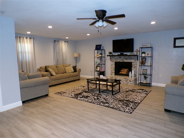 living room with a fireplace, light hardwood / wood-style flooring, and ceiling fan