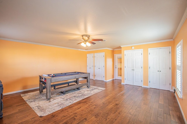 playroom with ceiling fan, dark hardwood / wood-style flooring, and ornamental molding