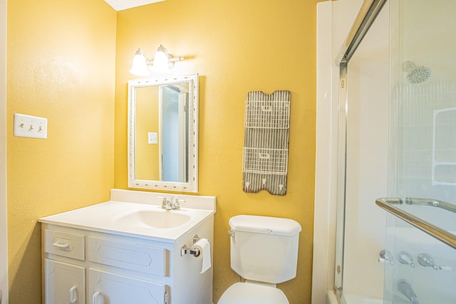 bathroom with an enclosed shower, vanity, and toilet