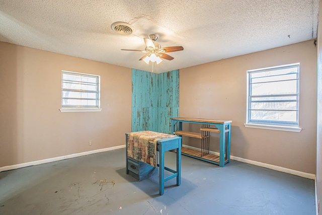 interior space with ceiling fan, plenty of natural light, and a textured ceiling