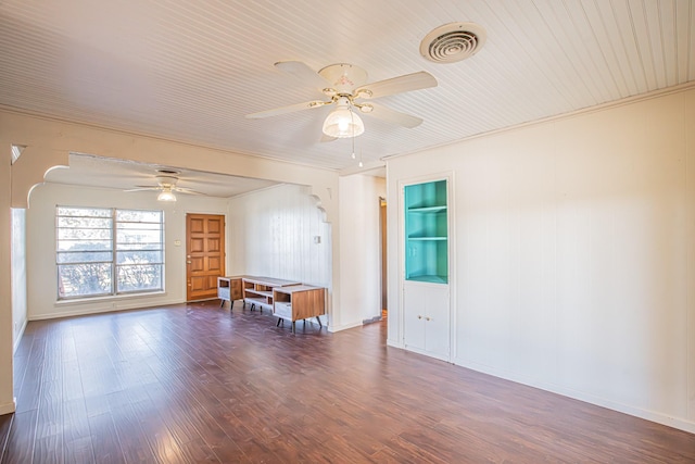 empty room with dark wood-type flooring, ceiling fan, built in features, and crown molding