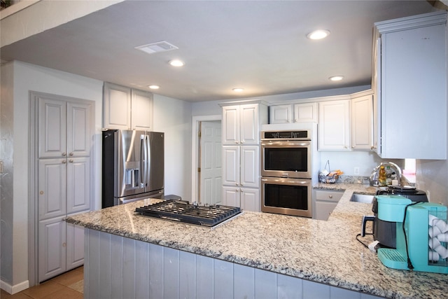 332 NW County Road 2005, Corsicana, TX 75110 - kitchen featuring stainless steel appliances, a peninsula, light stone countertops, recessed lighting, and white cabinetry