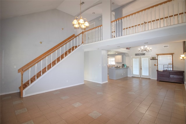 unfurnished living room featuring tile patterned floors, french doors, high vaulted ceiling, and a chandelier