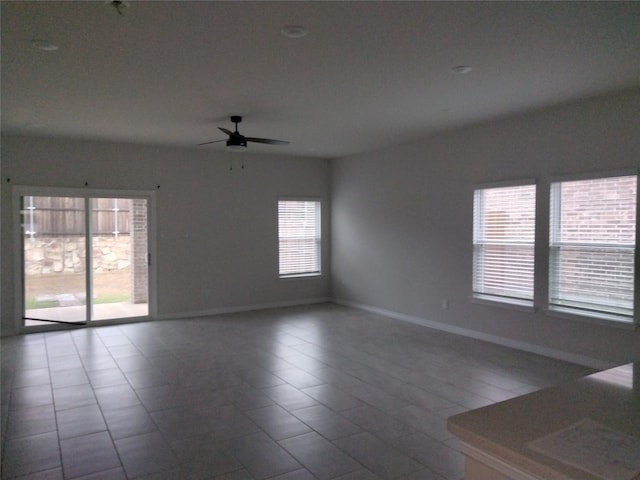 tiled empty room featuring ceiling fan and a healthy amount of sunlight