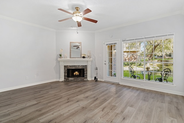 unfurnished living room with crown molding, ceiling fan, a high end fireplace, and hardwood / wood-style floors