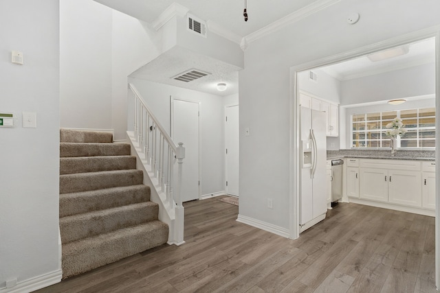 foyer with crown molding and light hardwood / wood-style flooring