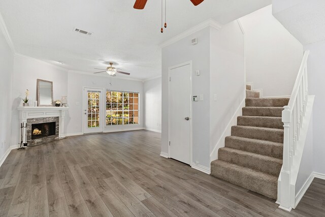 unfurnished living room with a fireplace, ceiling fan, hardwood / wood-style floors, and crown molding