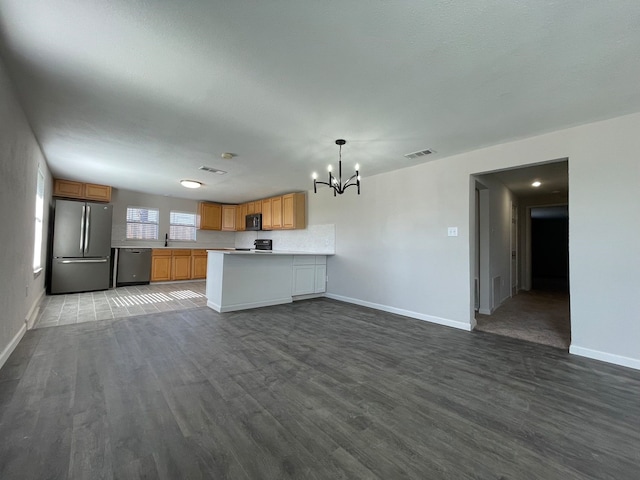 kitchen with black appliances, kitchen peninsula, hanging light fixtures, wood-type flooring, and a chandelier