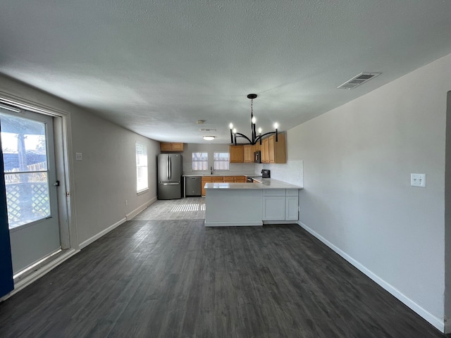 kitchen with an inviting chandelier, dark hardwood / wood-style floors, kitchen peninsula, a textured ceiling, and black appliances