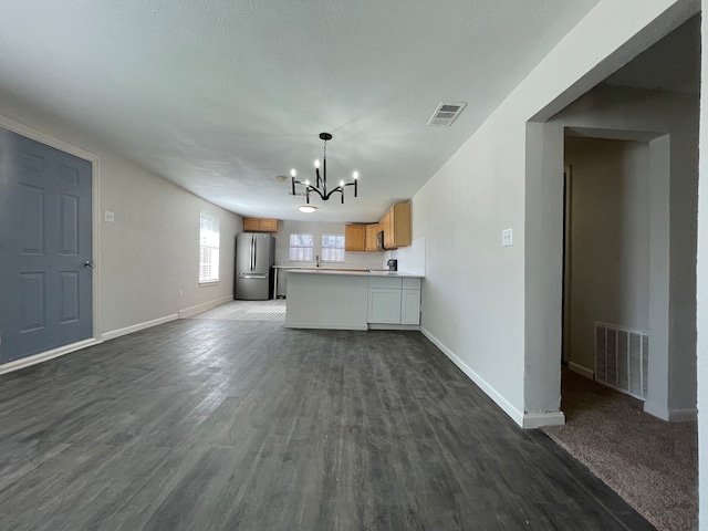 unfurnished living room featuring a chandelier and dark hardwood / wood-style floors