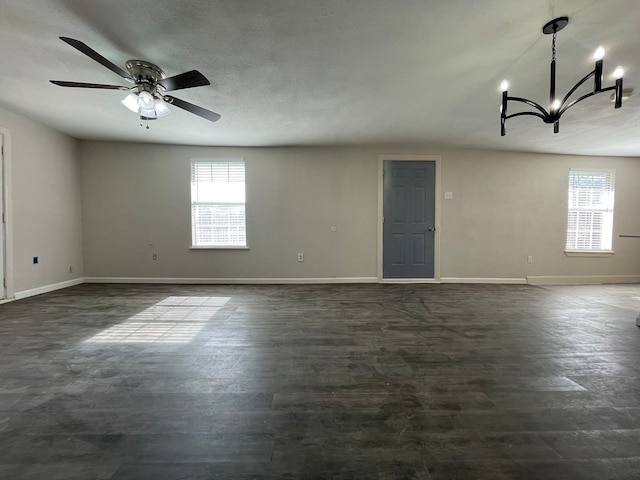 spare room with ceiling fan with notable chandelier, a healthy amount of sunlight, and a textured ceiling