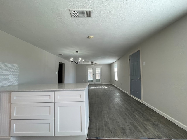 unfurnished living room featuring a textured ceiling, ceiling fan with notable chandelier, dark wood-type flooring, and french doors