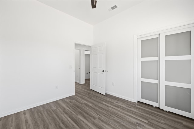 unfurnished bedroom with dark hardwood / wood-style flooring, a closet, and ceiling fan