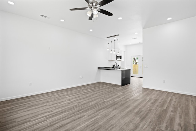 unfurnished living room featuring ceiling fan, dark wood-type flooring, and sink