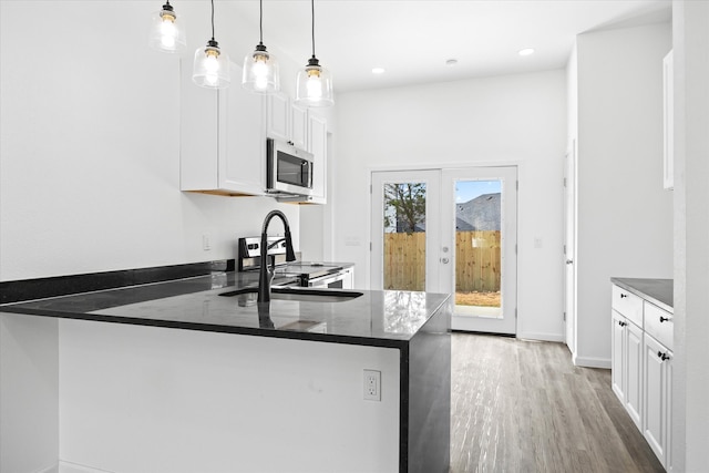 kitchen featuring white cabinets, decorative light fixtures, kitchen peninsula, and appliances with stainless steel finishes