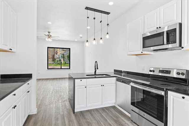 kitchen featuring kitchen peninsula, stainless steel appliances, sink, decorative light fixtures, and white cabinets