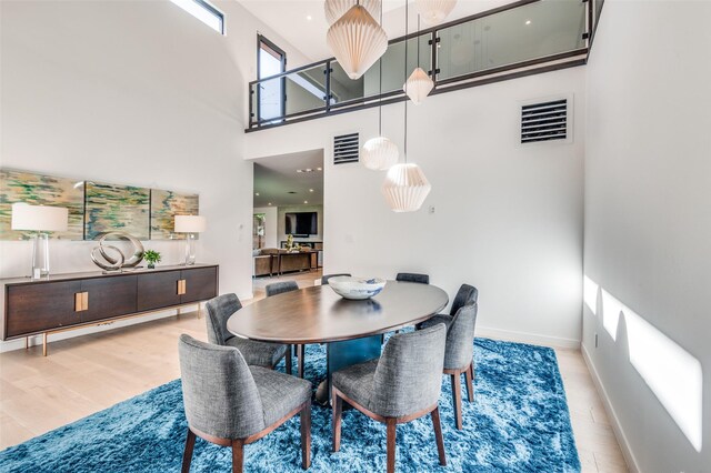 dining space featuring a towering ceiling and light hardwood / wood-style floors