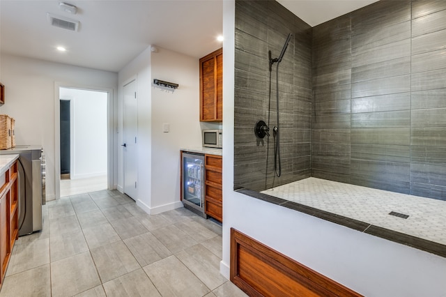 bathroom with washer / dryer, wine cooler, vanity, and tiled shower