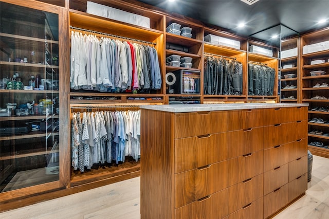 walk in closet with light hardwood / wood-style floors