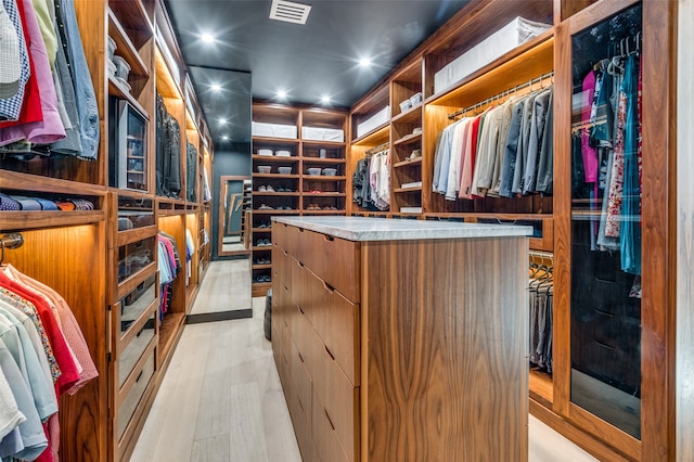 walk in closet with light hardwood / wood-style flooring