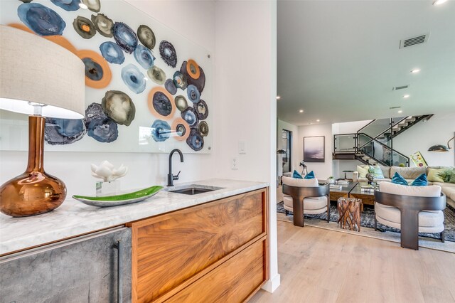 kitchen with light hardwood / wood-style floors, light stone counters, and sink