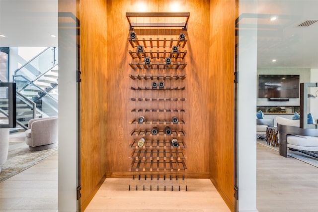 wine room with wood walls and light wood-type flooring