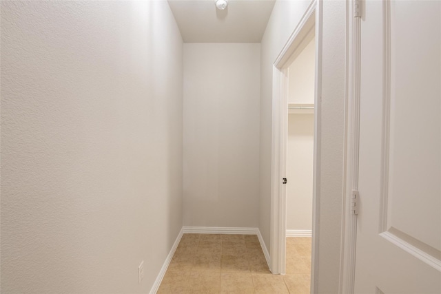 hallway featuring light tile patterned floors and baseboards