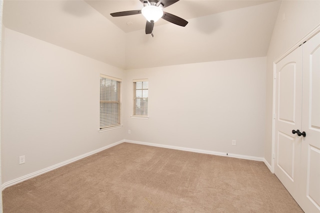 unfurnished room featuring a ceiling fan, lofted ceiling, light colored carpet, and baseboards