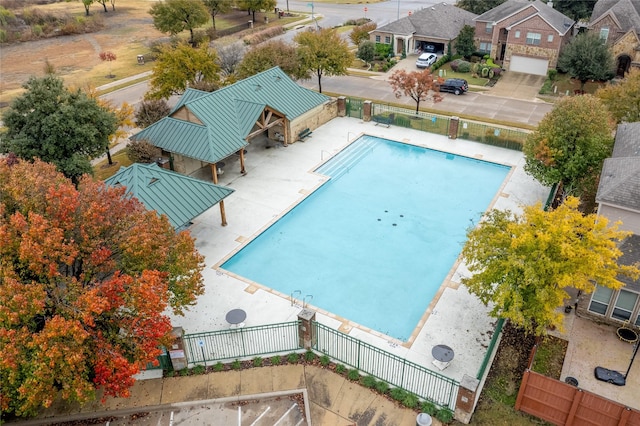 community pool with a patio, fence, and a residential view