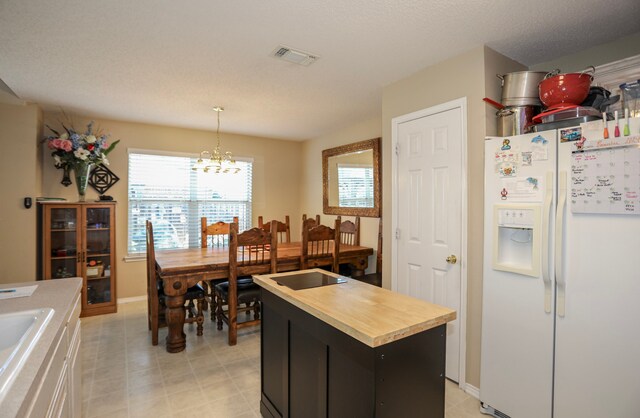 kitchen with white fridge with ice dispenser, a notable chandelier, butcher block countertops, pendant lighting, and a kitchen island