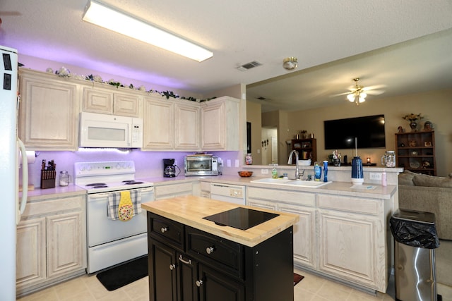 kitchen featuring a textured ceiling, sink, a kitchen island, and white appliances