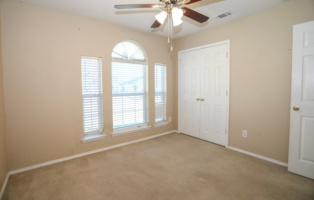 unfurnished bedroom with ceiling fan, light carpet, and a closet