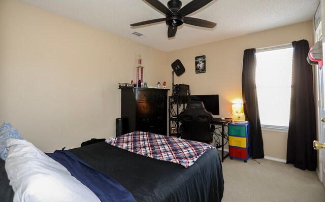 carpeted bedroom featuring ceiling fan, a textured ceiling, and multiple windows