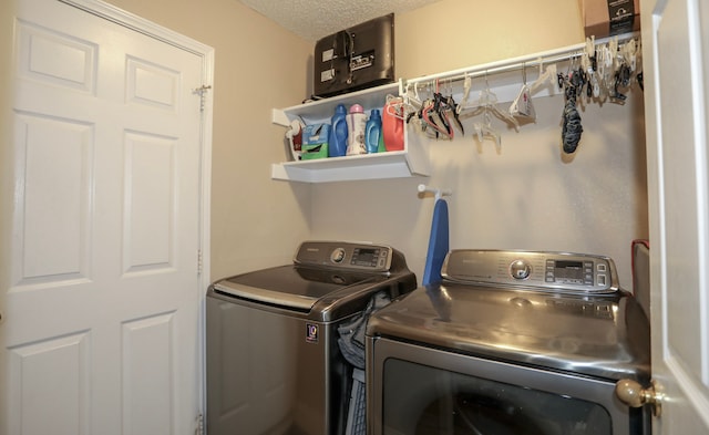 clothes washing area featuring washer and clothes dryer and a textured ceiling