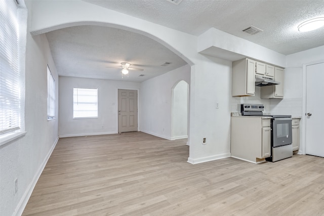 kitchen with stainless steel electric stove, ceiling fan, a textured ceiling, tasteful backsplash, and light hardwood / wood-style floors