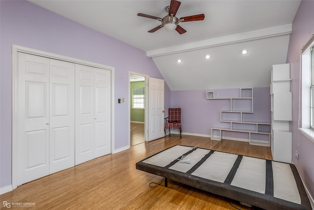 bedroom with lofted ceiling with beams, light hardwood / wood-style floors, ceiling fan, and multiple windows