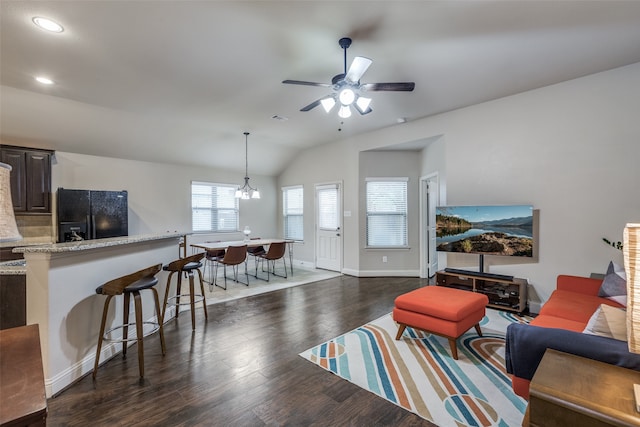 living room featuring dark hardwood / wood-style floors, ceiling fan with notable chandelier, and vaulted ceiling