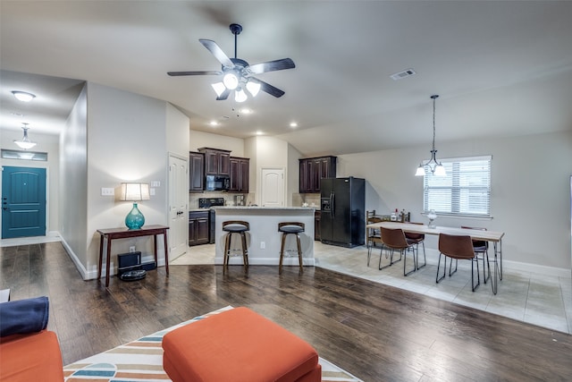 living room featuring light wood-type flooring, vaulted ceiling, and ceiling fan