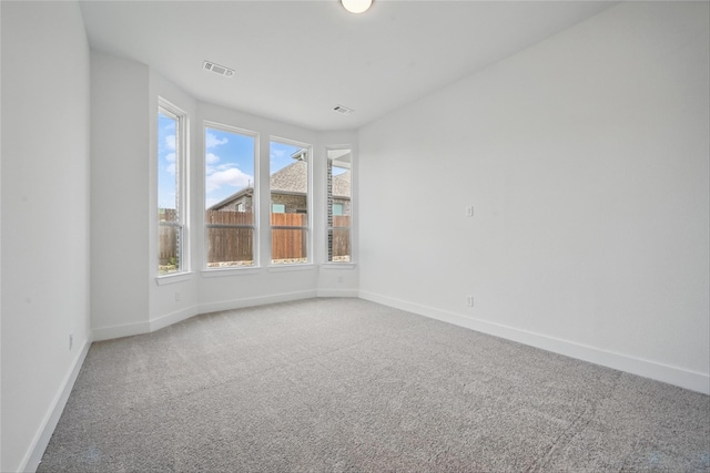 spare room featuring light colored carpet, baseboards, and visible vents