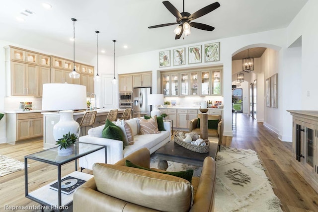 living room featuring ceiling fan with notable chandelier and light hardwood / wood-style floors