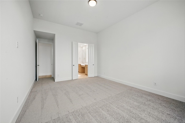 unfurnished bedroom featuring baseboards, visible vents, light colored carpet, and ensuite bathroom