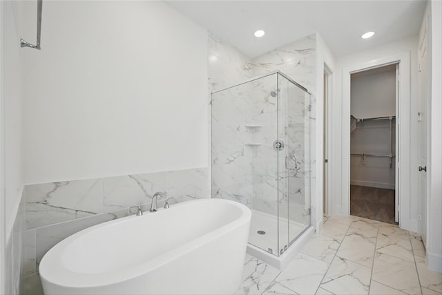 bathroom with a marble finish shower, a spacious closet, a freestanding tub, marble finish floor, and recessed lighting