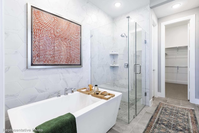 bathroom featuring tile patterned flooring, independent shower and bath, and tile walls