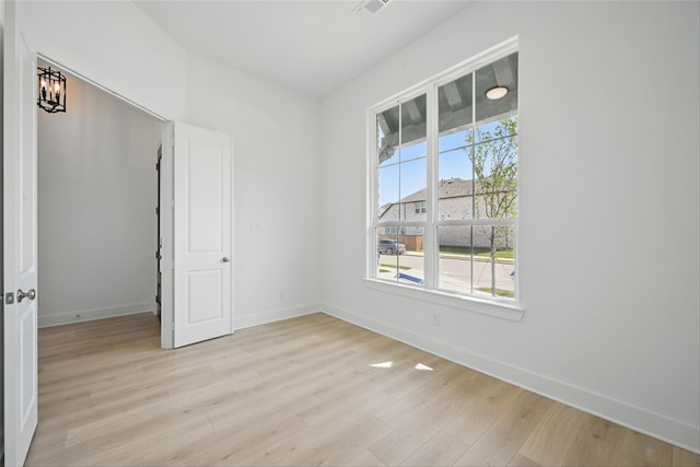 spare room featuring visible vents, light wood finished floors, and baseboards