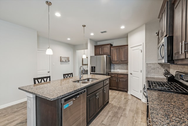 kitchen featuring appliances with stainless steel finishes, dark brown cabinetry, sink, a center island with sink, and light hardwood / wood-style floors