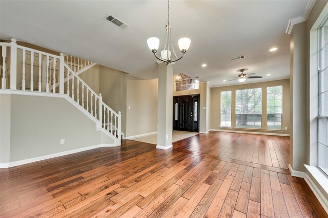 unfurnished living room featuring ceiling fan with notable chandelier, hardwood / wood-style flooring, and ornamental molding