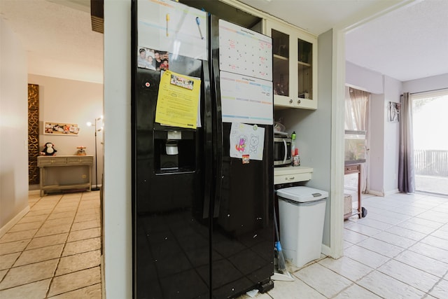 kitchen featuring black fridge with ice dispenser and light tile patterned floors